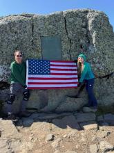 Pam and I holding the flag under the first ascent plaque