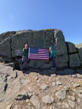 Pam and I holding the flag under the first ascent plaque